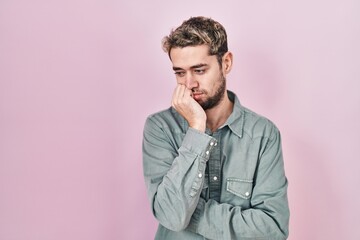 Hispanic man with beard standing over pink background thinking looking tired and bored with...