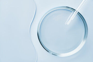 Empty round petri dish or glass slide and Pipette on blue background. Mockup for cosmetic or...