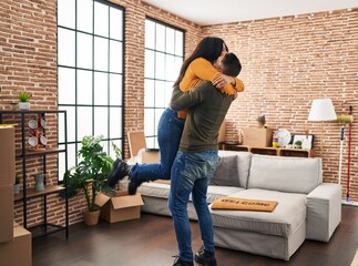 Fototapeta premium Man and woman couple hugging each other standing at new home