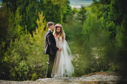 Portrait of young wedding couple are walking in the forest and admire nature and look at the landscape. Wedding ceremony and photo shoot outdoors. Newlyweds.