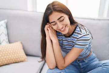 Young hispanic girl smiling confident sitting on sofa at home