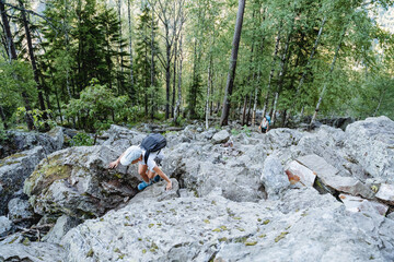 Family trip through the mountains, the boy climbs up the big stones, the trail passes through the kurum, the stone placer on the mountain, the dangerous route, trekking one