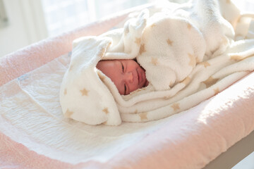 newborn baby wrapped in a soft starry blanket on a changing table after her bedtime bath routine. care and attention of the newborn baby