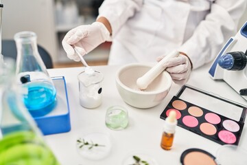 Young hispanic woman scientist making makeup working at laboratory
