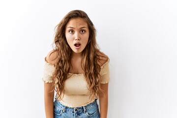 Beautiful hispanic woman standing over isolated while background afraid and shocked with surprise expression, fear and excited face.