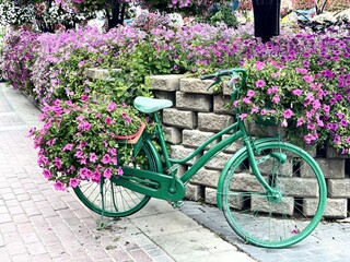 Fototapeta na wymiar Green bicycle with flowers in a park