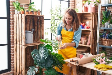 Young beautiful hispanic woman florist using difusser working at florist