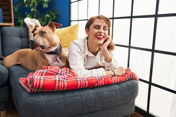 Young caucasian woman smiling confident lying on sofa with dog at home