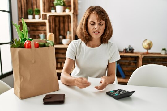 Young caucasian woman doing accounting of groceries purchase at home