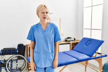 Beautiful caucasian physiotherapist woman working at pain recovery clinic winking looking at the camera with sexy expression, cheerful and happy face.