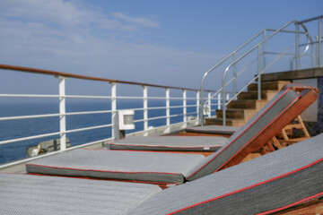 View from open outdoor deck of legendary luxury ocean liner cruise ship on passage during Transatlantic Crossing from Southampton to New York with deck chairs, railing and superstructure