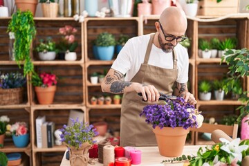 Young bald man florist cutting plant at florist
