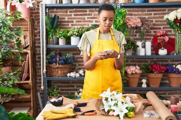 African american woman florist make photo to flowers by smartphone at florist