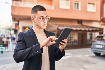 Young hispanic man executive using touchpad with serious expression at street