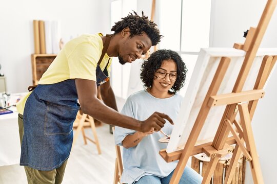 African american artist couple smiling happy painting at art studio.