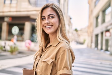 Young blonde girl smiling happy standing at the city.