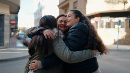 Fototapeta premium Mother and daugthers smiling confident hugging each other at street