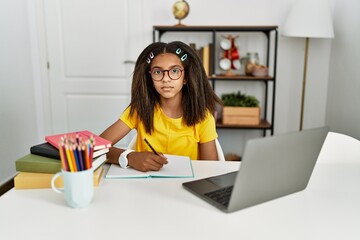 Young african american girl doing homework at home relaxed with serious expression on face. simple and natural looking at the camera.