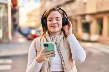Foto op Plexiglas Young blonde woman smiling confident listening to music at street © Krakenimages.com