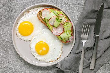 Healthy breakfast - a sandwich with avocado, cucumber and radish and stained eggs on a table
