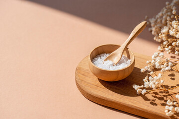 Wooden bowl with a spoon filled with white bath sea salt. Beauty treatment for spa and wellness on...