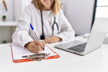 Fototapeta premium Young hispanic woman wearing doctor stethoscope working at clinic