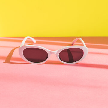 women's sunglasses in a white frame on a yellow and pink background. minimalism and pop art style.