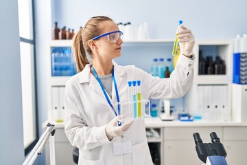 Fototapeta premium Young blonde woman wearing scientist uniform holding test tube at laboratory