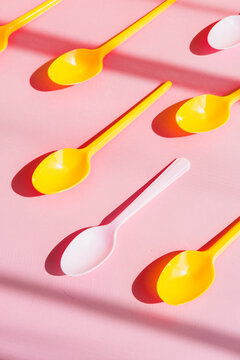 Plastic disposable ice cream spoons on a pink background.