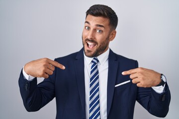 Handsome hispanic man wearing suit and tie looking confident with smile on face, pointing oneself with fingers proud and happy.