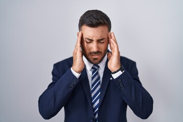 Handsome hispanic man wearing suit and tie with hand on head, headache because stress. suffering migraine.