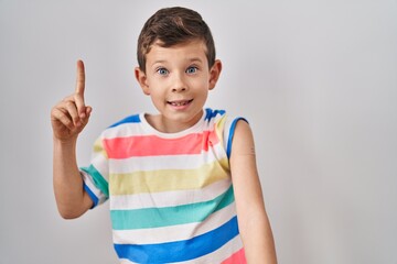Young caucasian kid getting vaccine showing arm with band aid smiling with an idea or question pointing finger with happy face, number one
