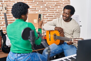 African american man and woman music group make photo holding spanish guitar at music studio