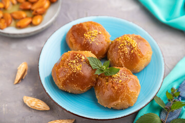 Traditional turkish dessert sekerpare with almonds and honey on gray concrete, side view, selective focus.