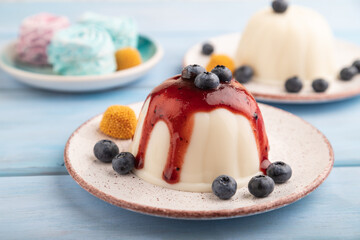 White milk jelly with blueberry jam on blue wooden,  side view, selective focus.