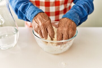 Senior man cooking dough at kitchen