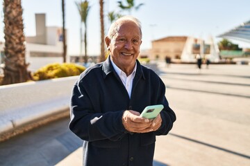 Fototapeta na wymiar Senior man smiling confident using smartphone at park