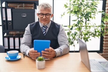 Middle age grey-haired man business worker using touchpad at office
