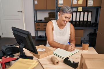 Middle age woman ecommerce business worker writing on book at office