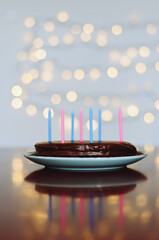 Festive birthday cake with burning candles against bright bokeh background. Greeting card. Party and holiday celebration concept.