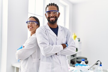 Man and woman scientist partners smiling confident standing with arms crossed gesture at laboratory