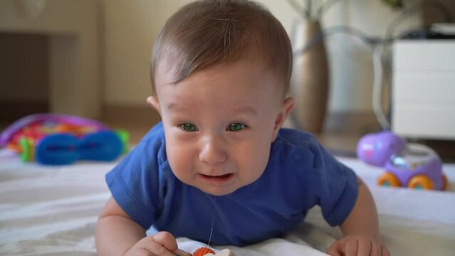 Green eyed baby crying on the floor. He is slobbering a little.