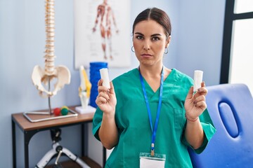 Young hispanic woman holding strip band for sprains skeptic and nervous, frowning upset because of...