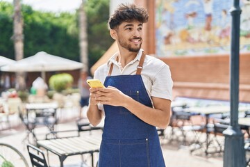 Young arab man waiter using smartphone working at restaurant