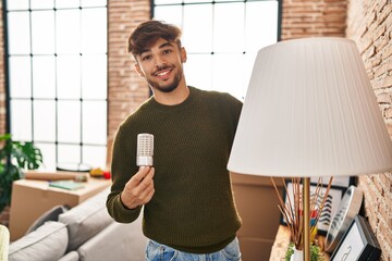 Young arab man smiling confident changing lightbulb at new home