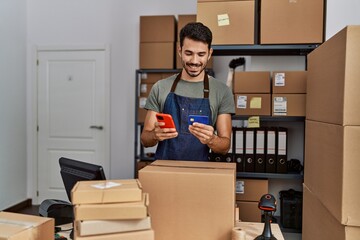 Young hispanic man business worker using smartphone and credit card at storehouse