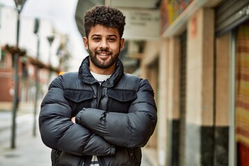 Young arab man smiling with crossed arms outdoor at the town