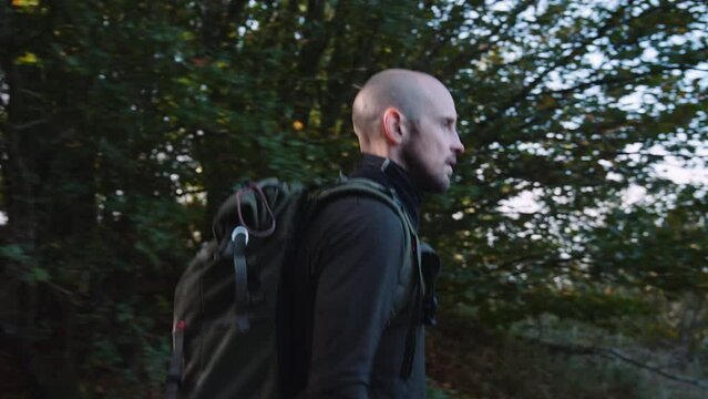 Side View of a Man Tourist with Backpack Hiking  Along the Trail in the Forest