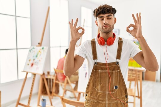 Young hispanic man at art studio relax and smiling with eyes closed doing meditation gesture with fingers. yoga concept.