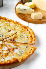 Pizza quattro formaggi on a wooden board .four cheese pizza and fresh ingredients for a four cheeses Italian pizza on a white wooden desk .